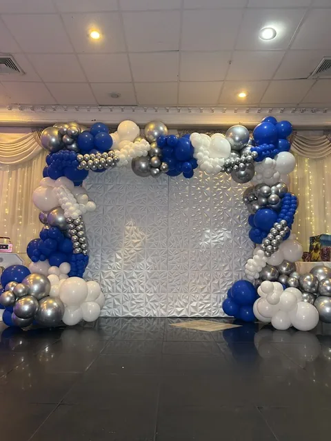 Blue, silver and white balloon arch framing an event backdrop